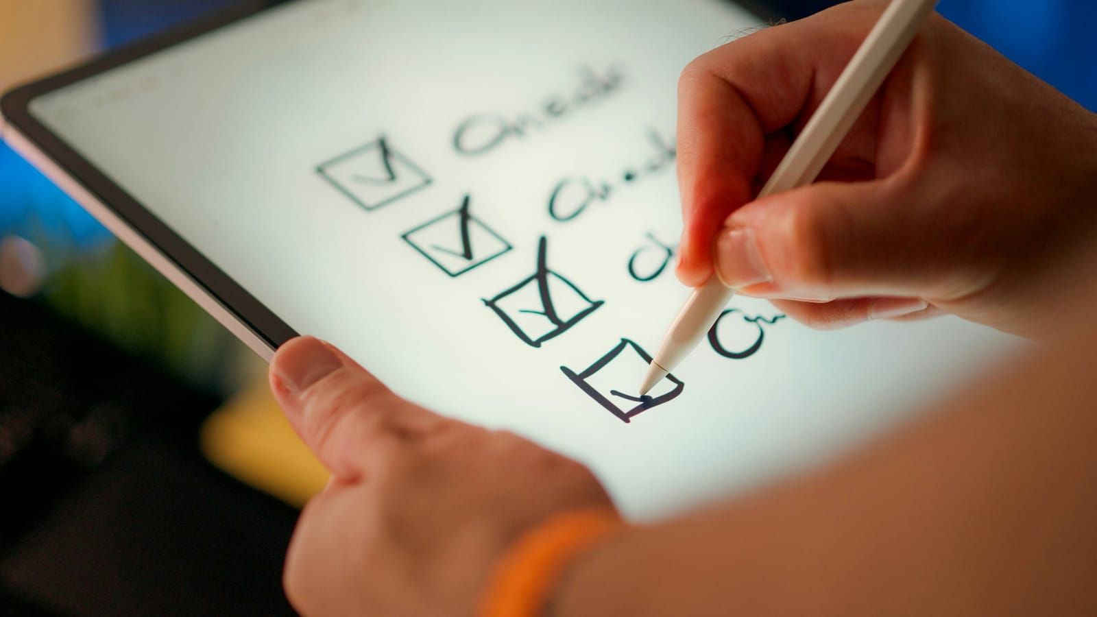 A hand ticking off a checklist on a tablet